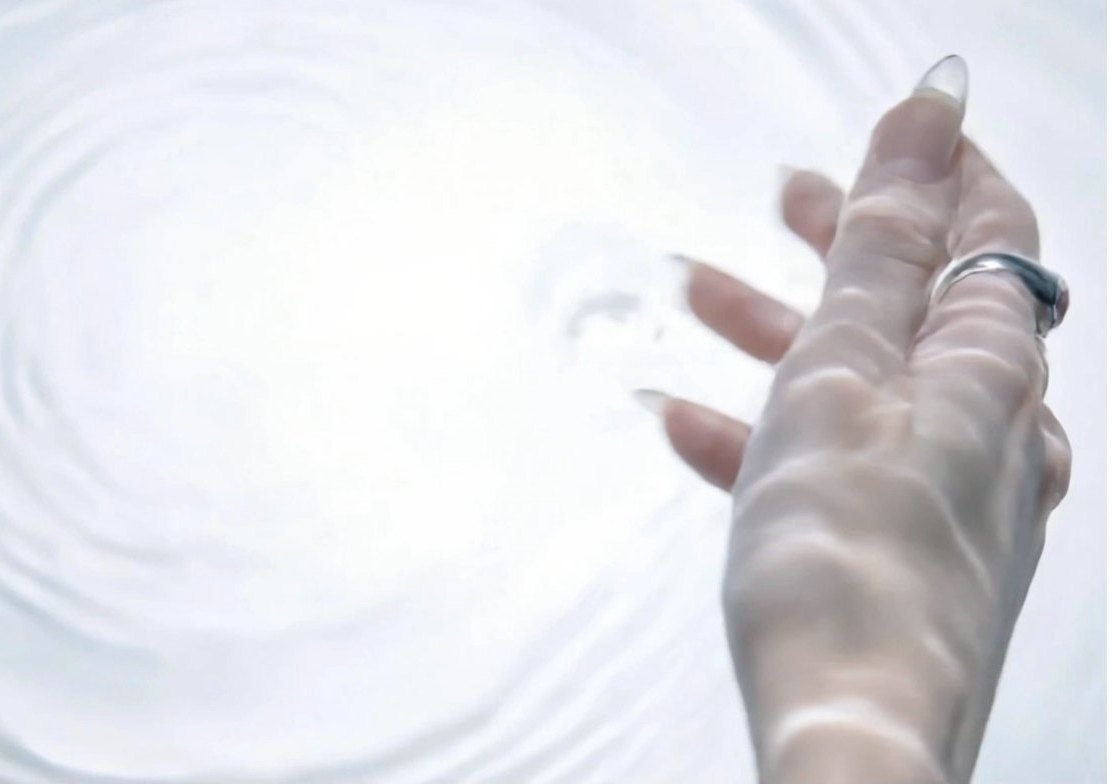 Hand wearing OYLA rings over water
